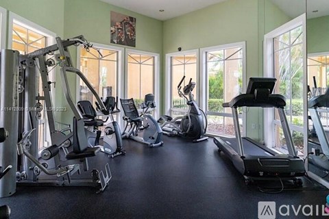 A gym with a variety of equipment including treadmills, elliptical machines, and weight machines.