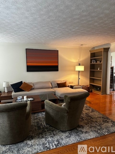 A living room with a couch, two chairs, and a painting on the wall.