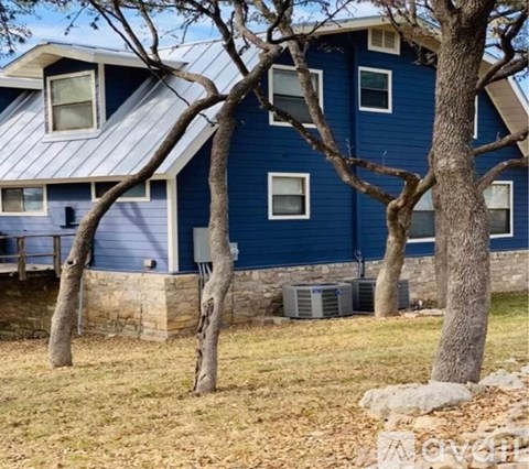A blue house with a metal roof and a stone wall.