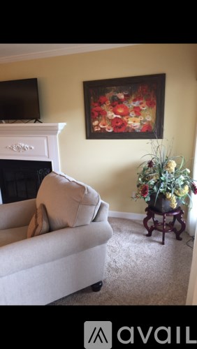 A living room with a white couch and a painting on the wall.