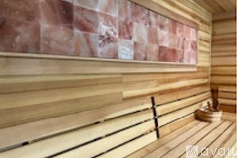 A wooden sauna with a bench and a bucket of water.