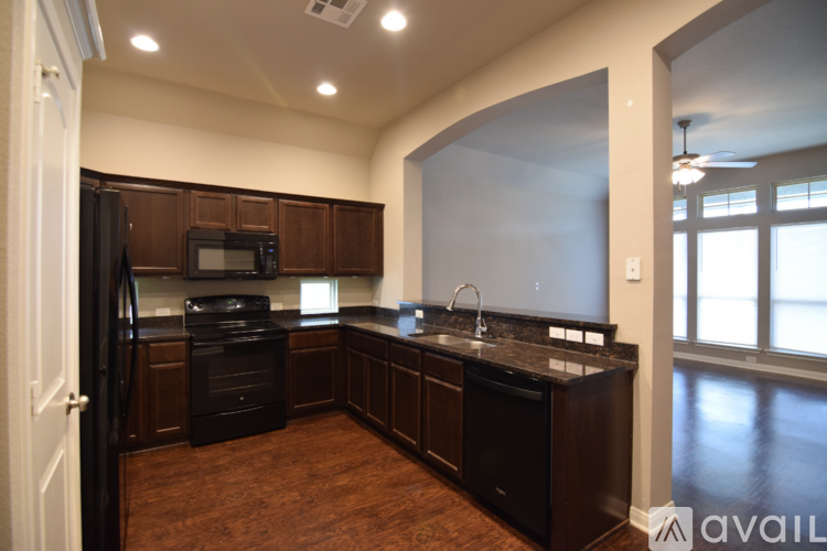 A kitchen with dark wood cabinets and black appliances.