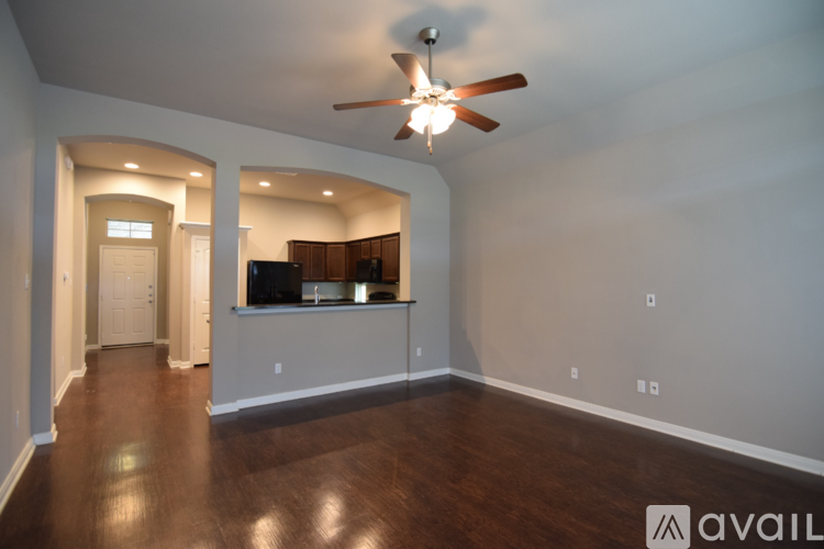 A spacious room with a ceiling fan and wooden flooring.