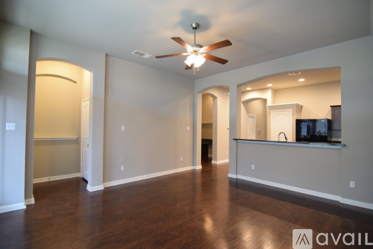 A spacious living room with a ceiling fan and hardwood floors.
