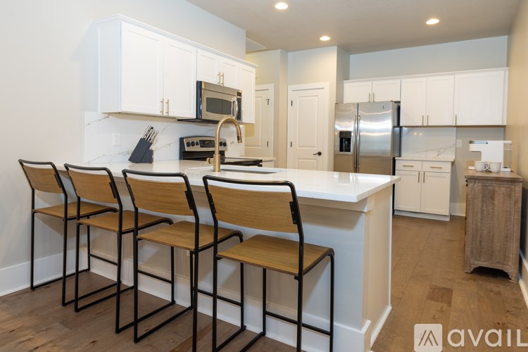 A kitchen with white cabinets and a white island with four chairs.