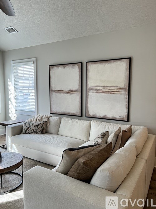 A living room with a white couch and two framed artworks on the wall.
