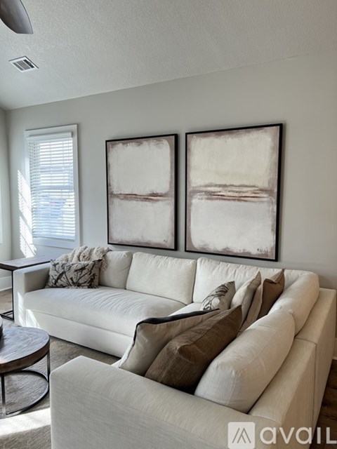 A living room with a white couch and two framed artworks on the wall.