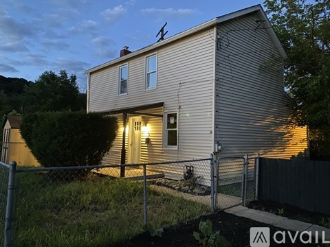 A house with a fence and a sign that says "AVAIL" in front of it.