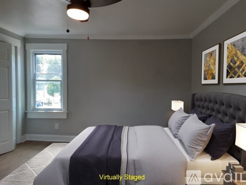 A bedroom with a bed, a window, and two pictures on the wall.