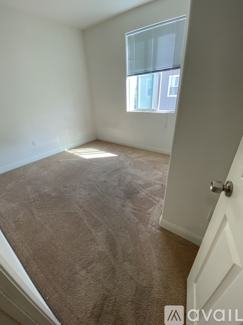 A room with a carpeted floor and a door leading to another room.