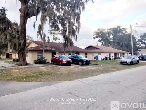 A row of houses with cars parked in front.
