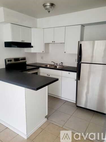 A kitchen with white cabinets and a black countertop.