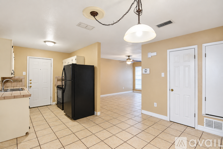 A kitchen area with a black refrigerator and cabinets.