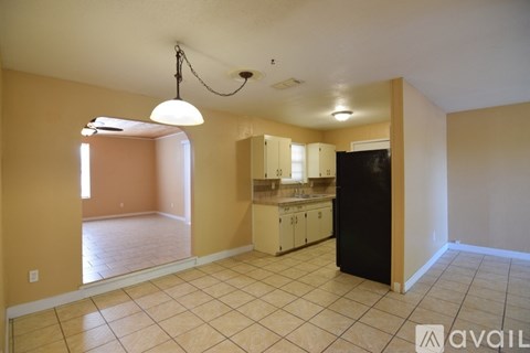 A kitchen area with a black refrigerator and cabinets.