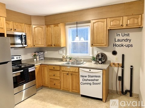 A kitchen with wooden cabinets and a sign that says "In Unit Laundry Hook-ups".
