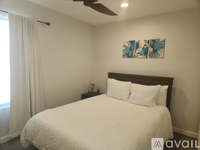 A bedroom with a large bed and a ceiling fan.