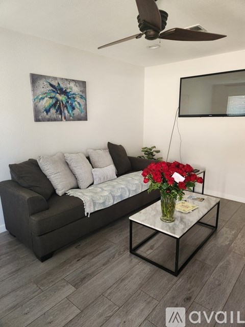 A living room with a grey couch, a coffee table, and a painting on the wall.