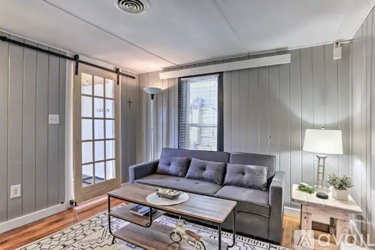 A grey couch sits in a living room with a coffee table in front of it.