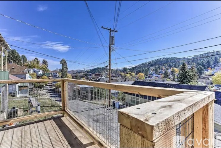 A wooden deck with a railing overlooking a residential area.