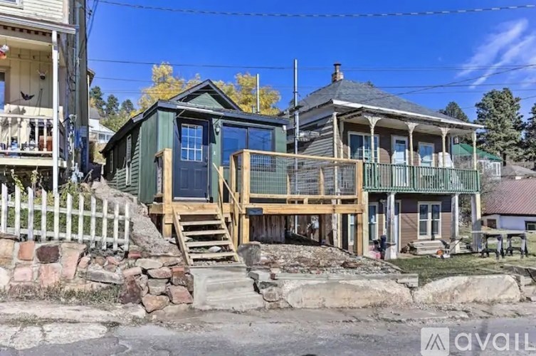 A house with a green porch and a white picket fence.