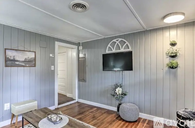 A living room with a grey wall and a black television.