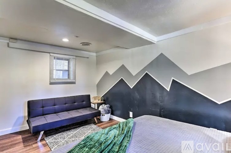 A bedroom with a bed, a sofa, and a wall mural.