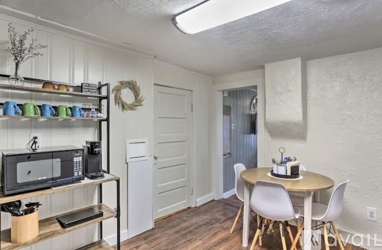 A kitchen with a table and chairs and a microwave on a shelf.