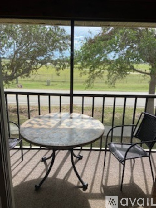 A patio with a table and chairs overlooking a grassy field.