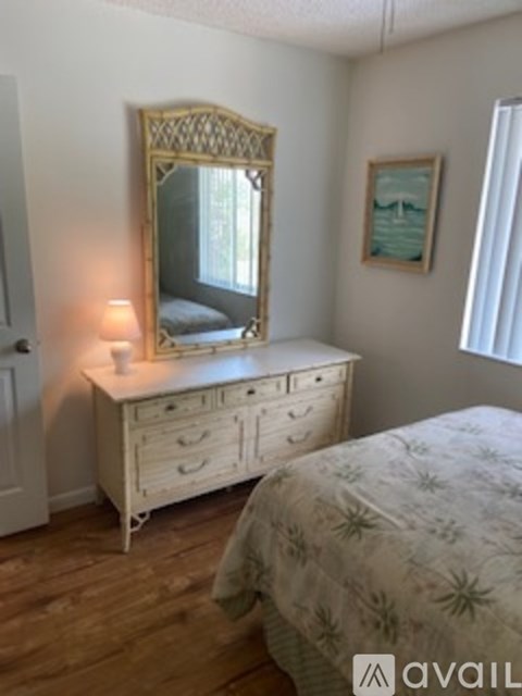 A bedroom with a bed, a dresser with a mirror and a painting on the wall.