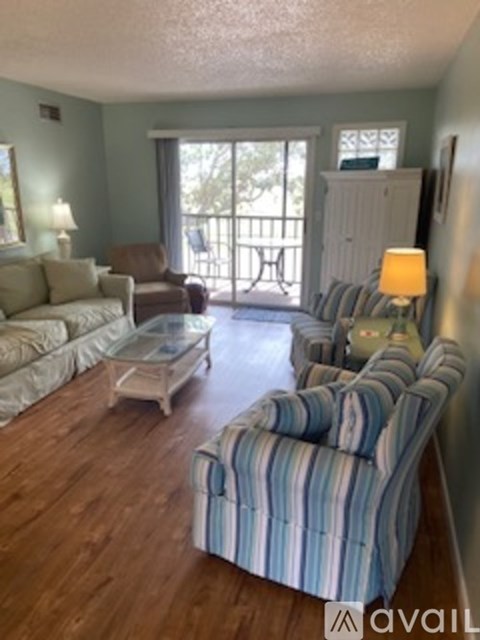 A living room with a striped couch and a glass coffee table.