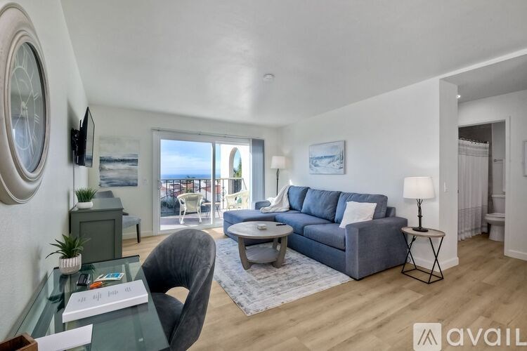 A living room with a grey sofa, a glass table, and a chair.