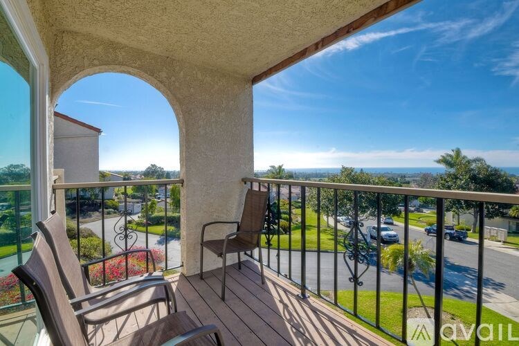 A balcony with a table and chairs overlooking a street.