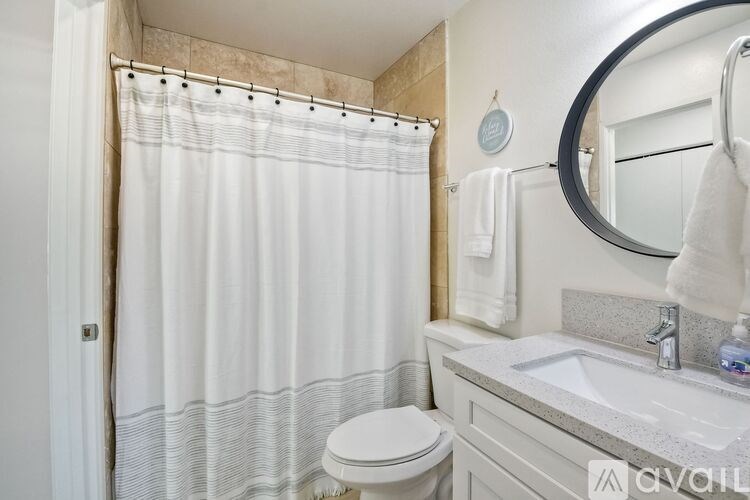 A bathroom with a white toilet, a white sink, and a white shower curtain.