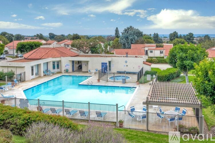 A large outdoor swimming pool surrounded by a fence and lounge chairs.