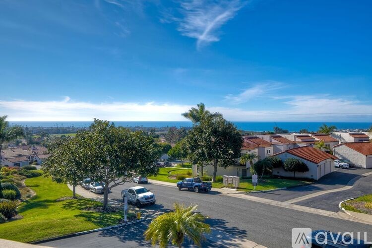 A sunny day in a residential area with houses and cars.