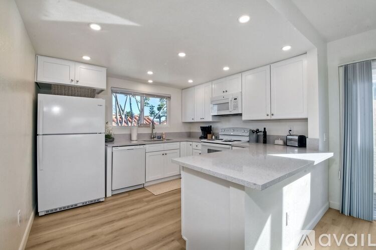 A modern kitchen with white cabinets and appliances.