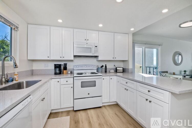 A modern kitchen with white cabinets and appliances.