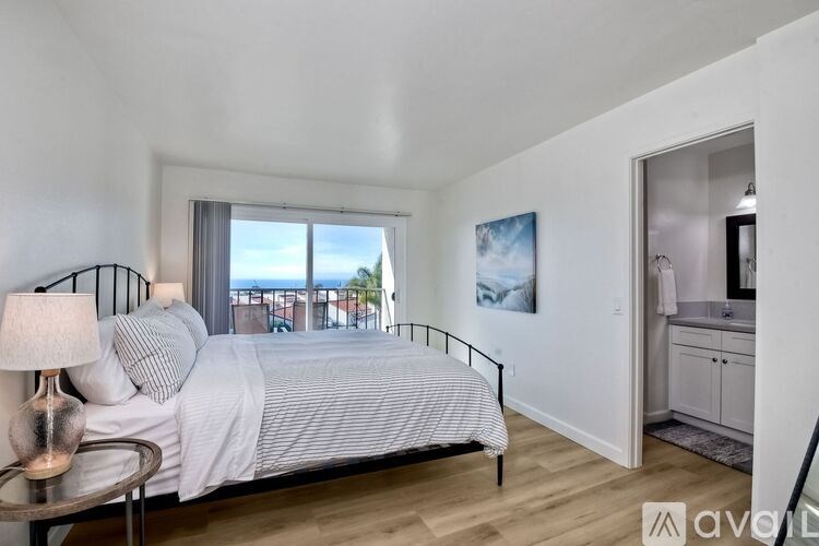A bedroom with a large bed and a balcony overlooking the water.