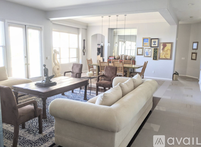 A living room with a white couch and wooden chairs.