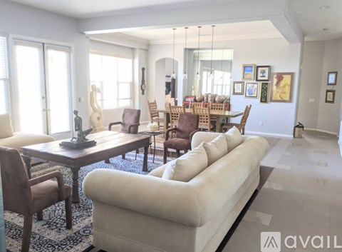 A living room with a white couch and wooden chairs.