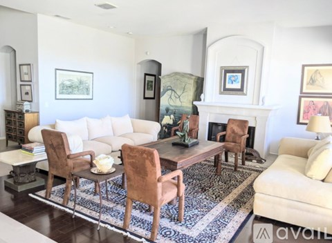 A living room with a white couch, brown chairs, and a fireplace.
