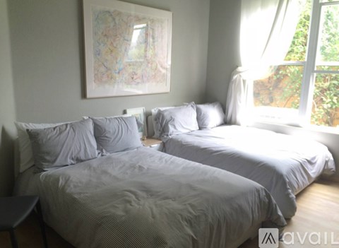 Two beds with white pillows in a room with a painting on the wall.