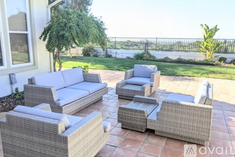 A patio with a white couch, grey couch, and grey chair.
