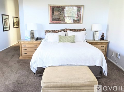 A bedroom with a large bed, two nightstands, and a bench in front of the bed.