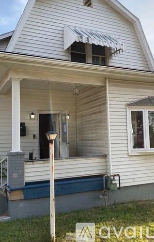 A white house with a porch and a lamp post.