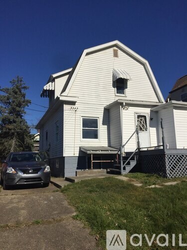A white house with a car parked in front.