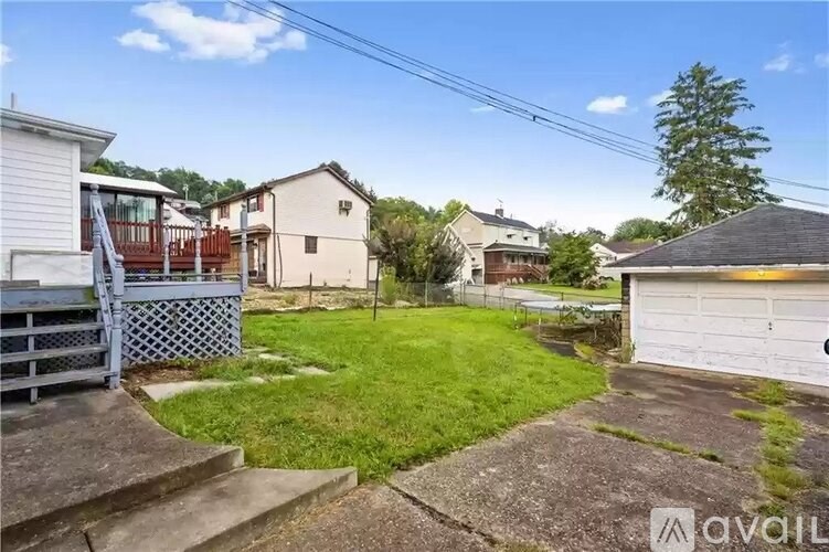 A backyard with a white house, a green lawn, and a white garage.