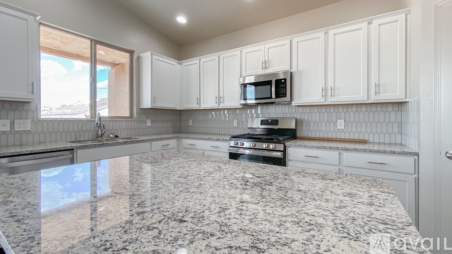 A kitchen with granite countertops and white cabinets.