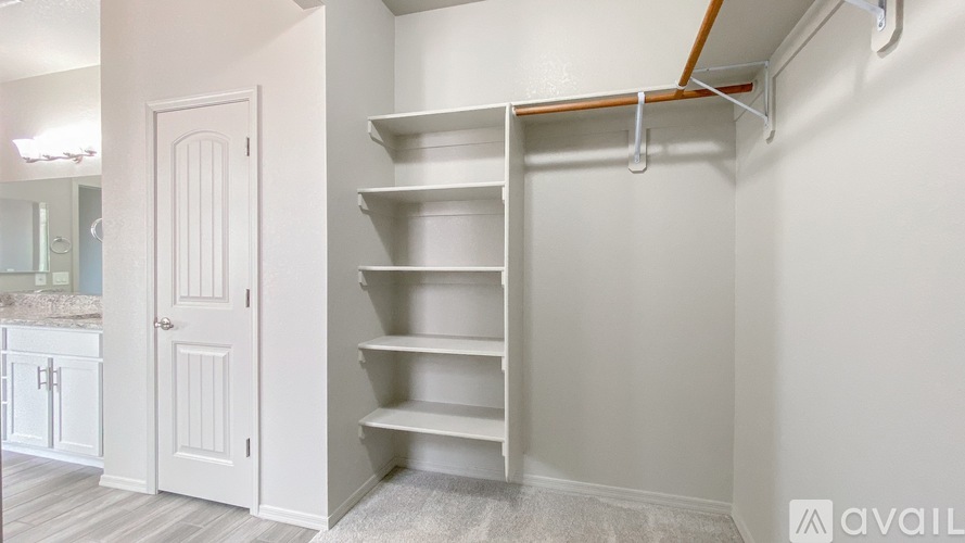 A white shelving unit in a room with a white door.