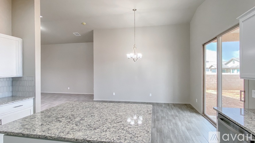 A spacious kitchen with granite countertops and a chandelier.